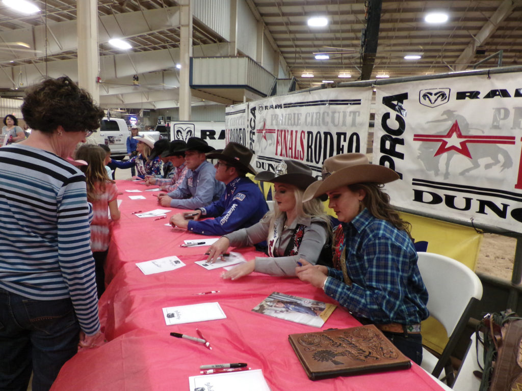 Rodeo Queens and event winners sign autographs for fans.